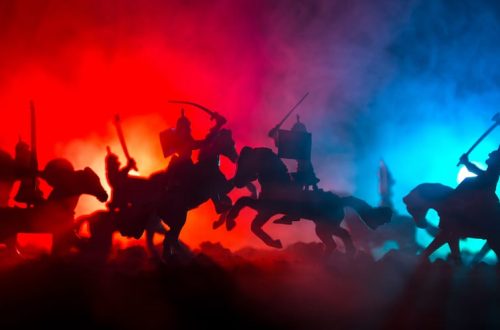 Medieval battle scene with cavalry and infantry. Silhouettes of figures as separate objects, fight between warriors on dark toned foggy background. Night scene. Selective focus